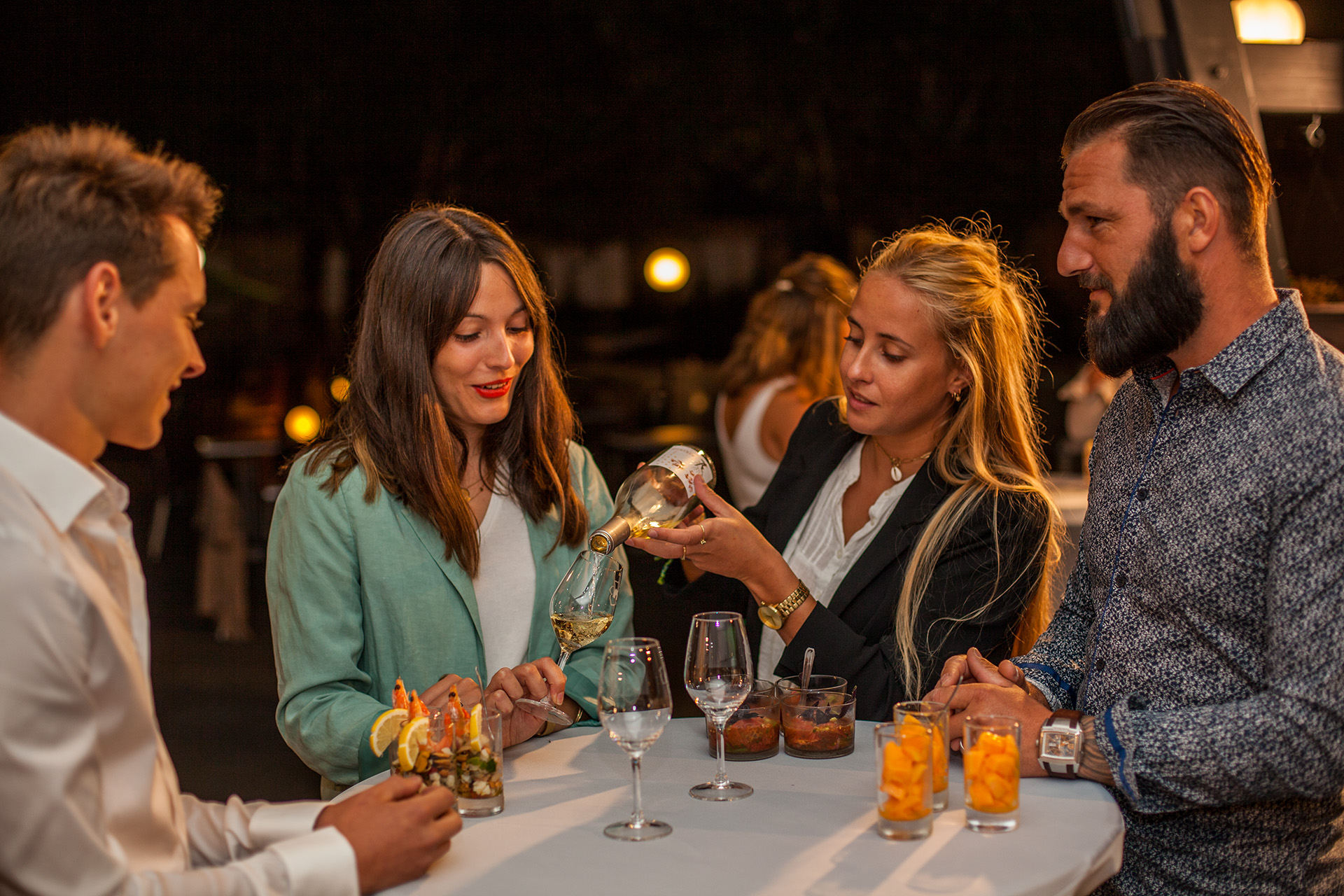 Personnes en train de boire et discuter autour d'une table lors d'un cocktail au restaurant de groupes Les Tablées de L'Oustal