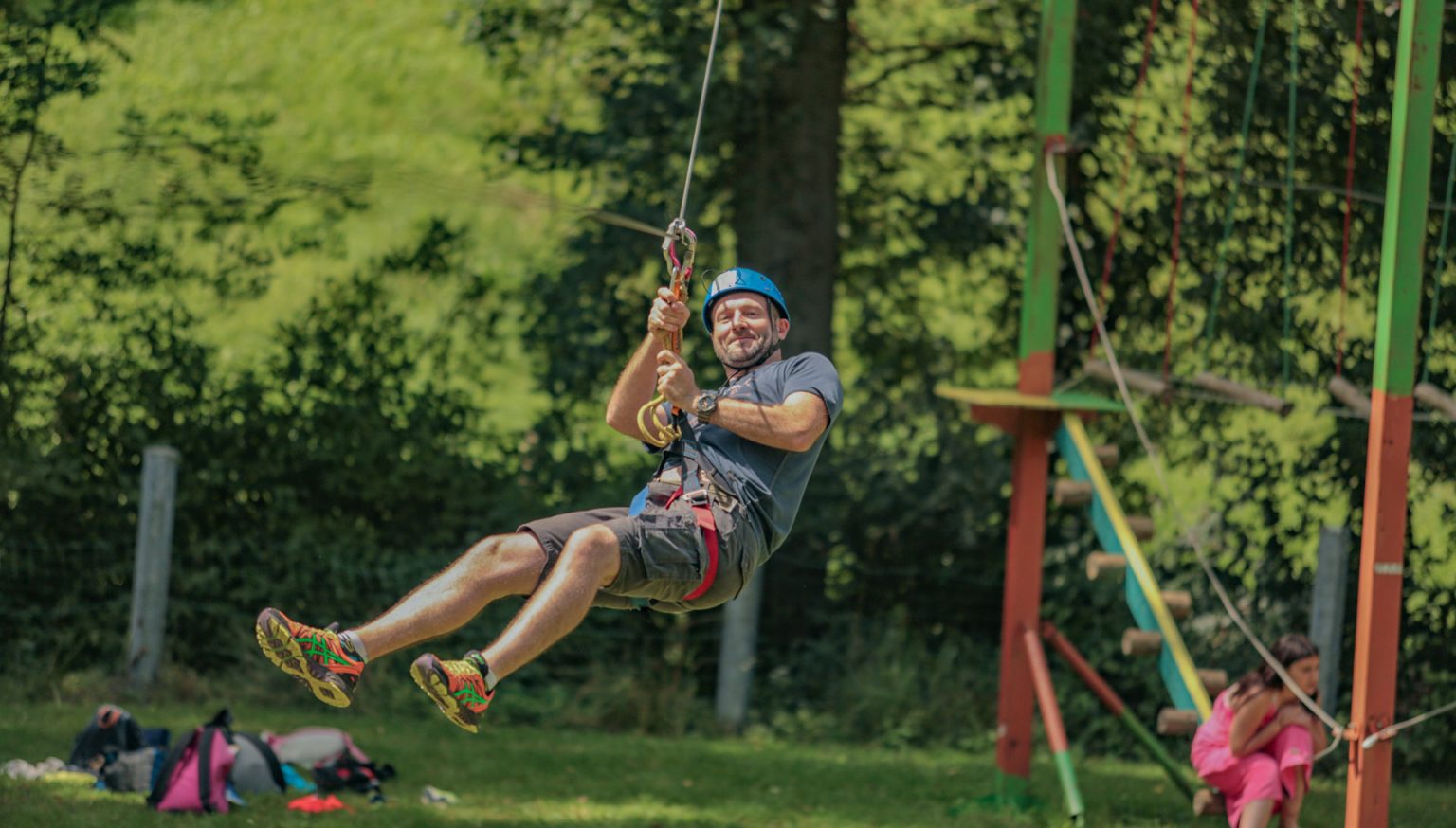 Adulte en pleine descente de tyrolienne au parcours accrobranche du parc aventure de la vallée de Vanc à L'Oustal Pont-les-Bains en Aveyron