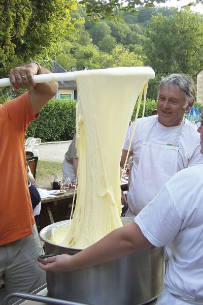 clients et cuisiners font filer l'aligot dans une énorme marmite au restaurant de groupes Les Tablées de L'Oustal en Aveyron